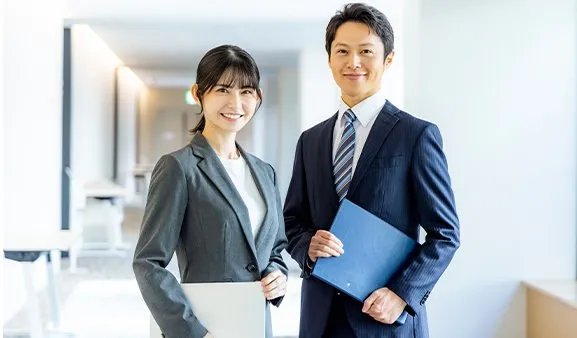 スーツ姿の男女が笑顔で並ぶ