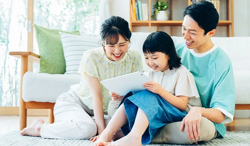 リビングでタブレットを見て笑う家族