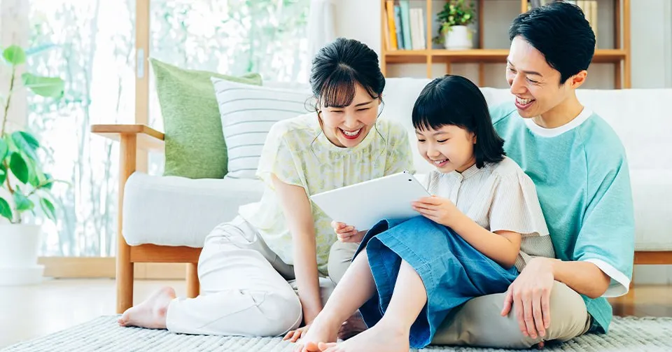リビングでタブレットを見て笑う家族