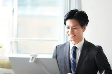 パソコンに向かって微笑むスーツ姿の男性